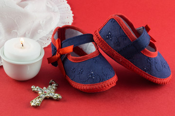 Christening background with navy and red booties, candle and cross