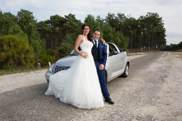 Lovely cute groom and bride on a grey convertible car posing