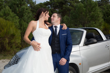 Lovely cute groom and bride on a grey convertible car posing