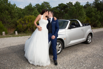 Lovely cute groom and bride on a grey convertible car posing