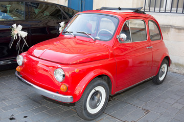 Red small retro car at the city street
