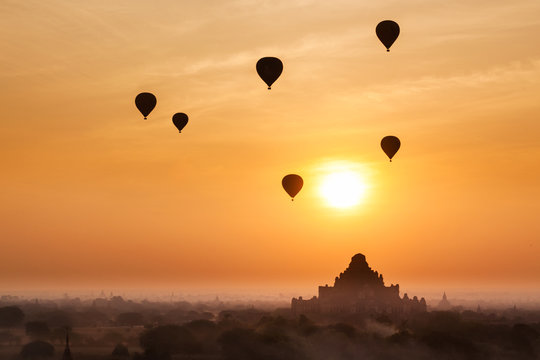Old bagan in morning mist and silhouette of hot air balloon, tourists watching sunrise over ancient city, Myanmar (Soft focus)