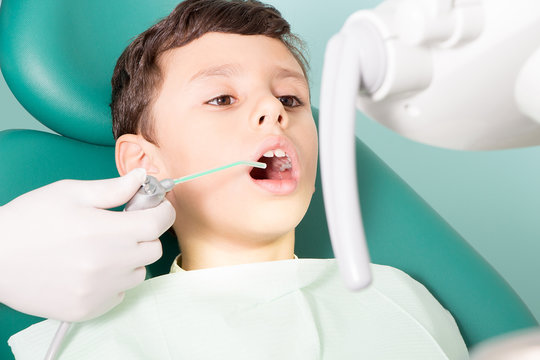 Dentist examining kid's teeth at dental clinic