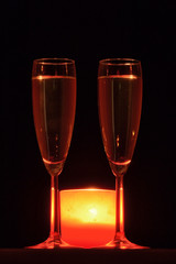 2 copas de cava y una vela roja. Aislado en fondo negro.
