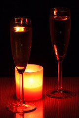 2 copas de cava y una vela roja. Aislado en fondo negro.