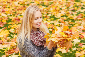 Young, beautiful, gentle woman enjoying autumn time with colorful leaves in the park.