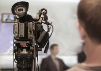 Abstract blurred background of video cameras recording in press conference.