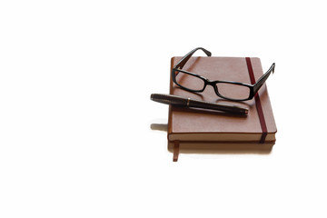 Glasses and pen on top of brown agenda with white background