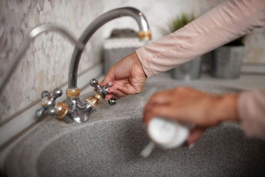 Woman hand washing cup over the sink in the kitchen