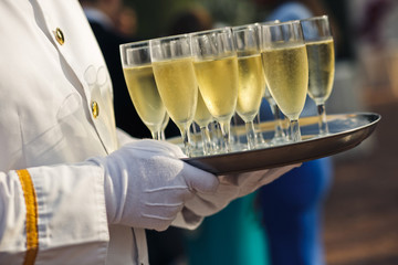 Server with many goblets of the champagne on the wedding