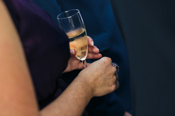 Woman is holding a goblet of the champagne on the wedding