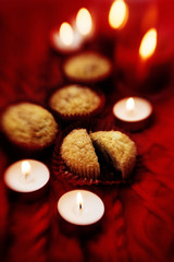 Soft focus. Muffins in a red wrapper on red knitted sweater, red candles and bokeh. Christmas atmosphere