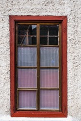 Rotes Holzkastenfenster mit Gardinen