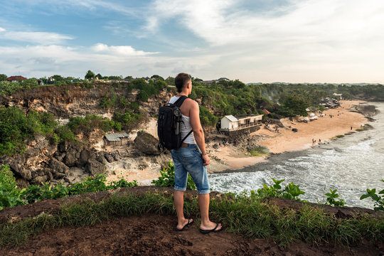Man with backpack looking forward from the cliff  on Balangan beach. Bali. Indonesia
