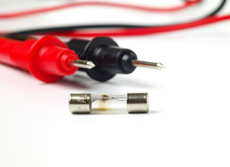 blown fuse macro with multimeter probes in background, white background, shallow depth of field