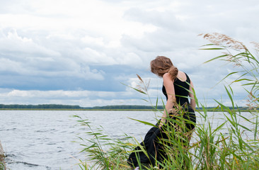 Молодая женщина в черном платье на берегу озера © anch87189