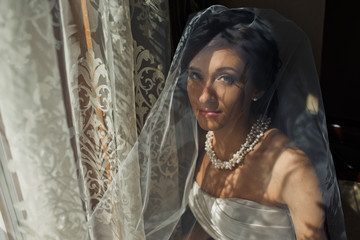 The beautiful bride stands near window
