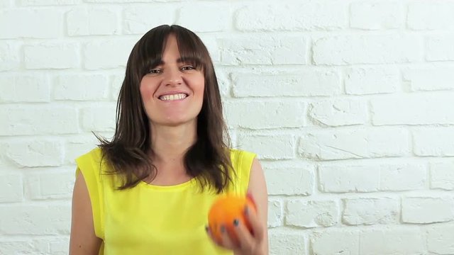 Happy young woman juggling oranges, slow motion