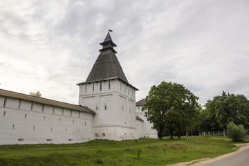 Fototapeta na wymiar The white wall of the monastery and square hipped tower.
