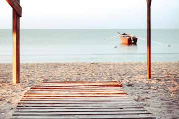 Empty wooden table or shelf wall with view of sunset or sunrise and boat on sand beach background. For present your products.