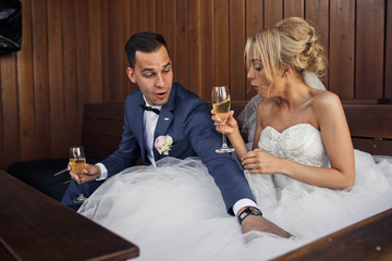 young groom and bride drink champagne in cafe