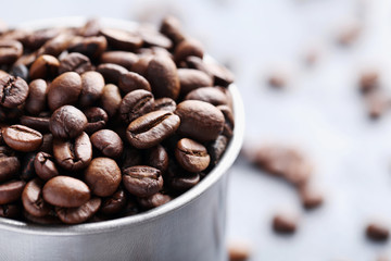 Roasted coffee beans in mug on grey table