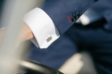 Silver cufflink on the white shirt of the groom