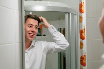 Charming smile of the young groom in the mirror