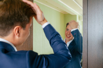 Groom is preparing to the wedding in front of the mirror