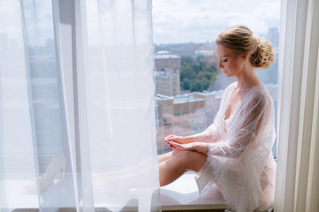 Sensual bride in the lace robe  on the window
