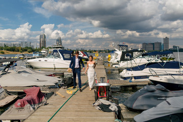 Newlyweds are walking on the moorage with the yachts