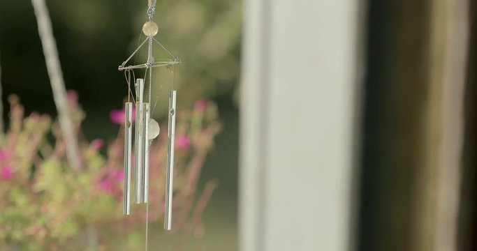 Windchimes blow in the wind, handheld with shallow focus.