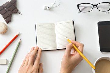 Student female hands holding a pencil and open notebook. Office supplies around. Education concept photo, close up, copy space