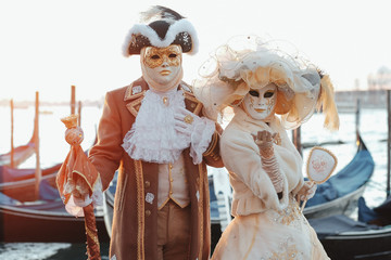 Pretty couple in rich white and golden carnival costumes poses o