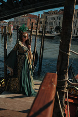 Fototapeta na wymiar Pretty woman in green dress waits on the berth for a gondola