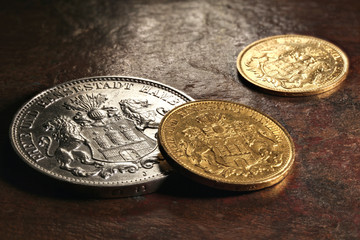 Hamburg silver and gold coins (German Empire Mark) on rustic wooden background