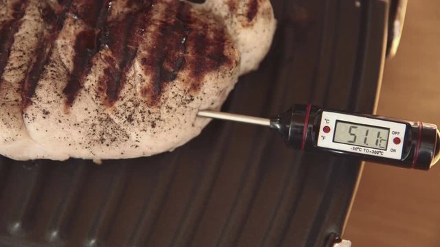 Thermometer for meat set in a large steak that is on elektrogrile shows the temperature and the degree of readiness of steak