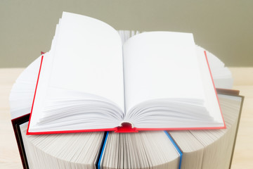 Open book, stack of hardback books on wooden table. Back to scho