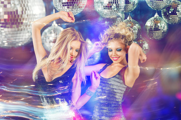 Two young women dancing at night disco club