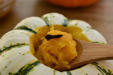 Closeup on baked mini-pumpkin stuffed with spiced pumpkin puree, served with a clove, viewed from the side- seasonal food concept