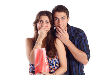 Young couple watching a scary movie and eating popcorn.