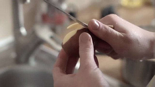 woman's hands peeling potatoes in the kitchen