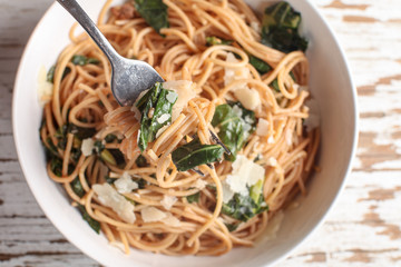 Kale, Tomato and Parmesan pasta dish top view with fork full of food