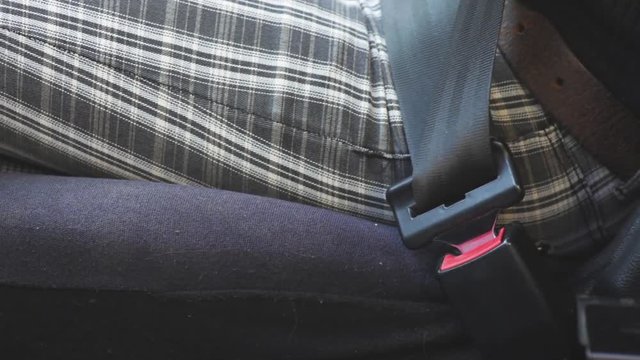 Color footage of a woman fastening the seat belt.