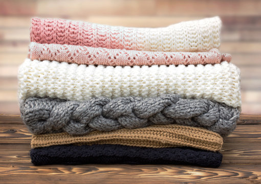 Winter knitted clothes stack on wooden background.
