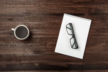 Glasses and notebook on dark table with coffee