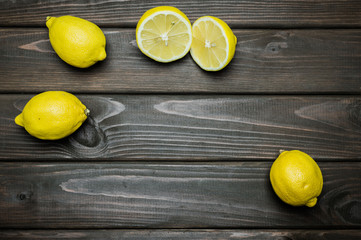 Whole and cut lemons on grey wooden surface