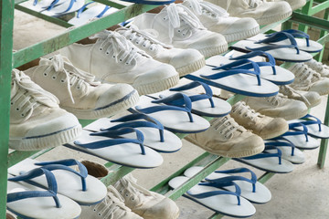 White sneakers and sandals lay on the old green shoes rack orderly