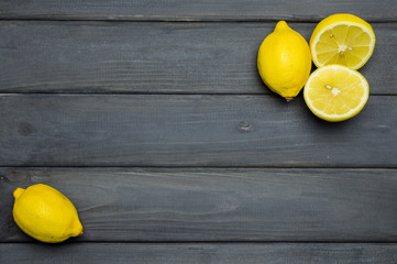 Whole and cut lemons on grey wooden surface