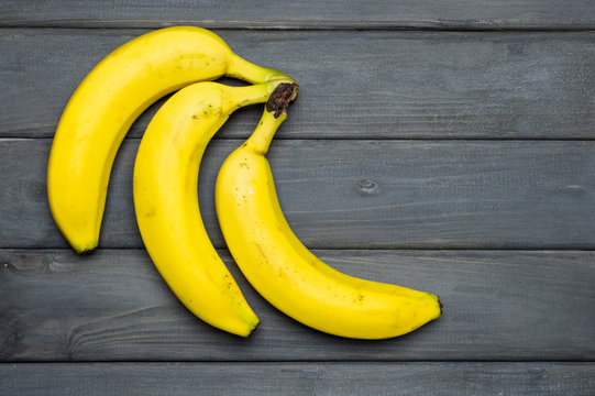 Yellow bananas on grey wooden surface